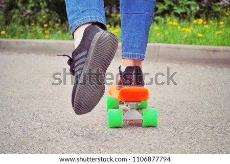 Penny Board and legs on road . Orange pennyboard with green wheels