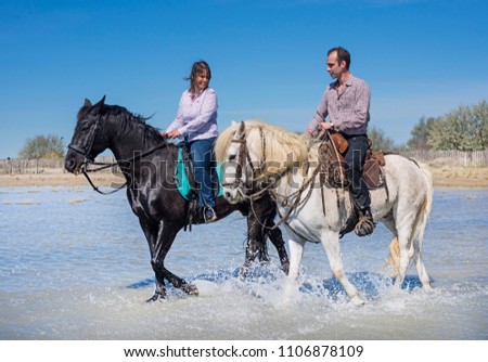 woman and man riding with her stallion on the beach