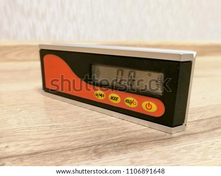 Professional digital tool inclinometer on the wooden floor for leveling and inclination measurements