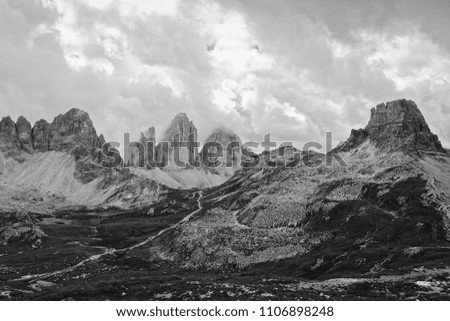 The famous Tre Cime di Lavaredo - Drei Zinnen - of the Sesto Dolomites with a mountain hut and a dramatic sky, black and white photo, South Tyrol, Alps, Italy