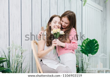 Happy family,mother and cute girl. Daughter giving flowers to her motherat home in living room.Relationship of mother and daughter concept.Family concept.