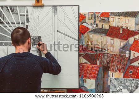 Concentrated male artist is drawing a dog on easel in his art studio, colorful pictures, creative atmosphere
