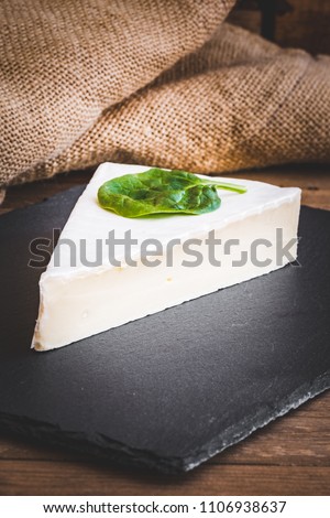 portion of brie cheese camenbert on wood cutting board