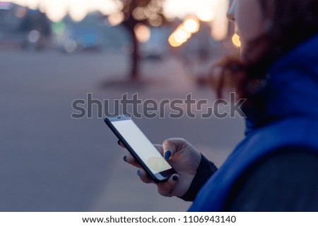 young woman walking in the night city streets using modern smartpone  with blank screen with copy space for your text or logo, mock up of modern smartphone device