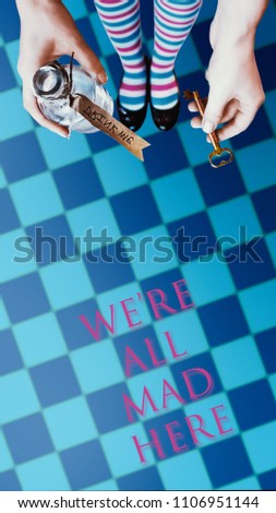 Alice in wonderland. Background. A key and a potion in hands against a  chess floor