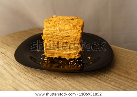 Slice of orange cake on black plate on the wooden table, food background