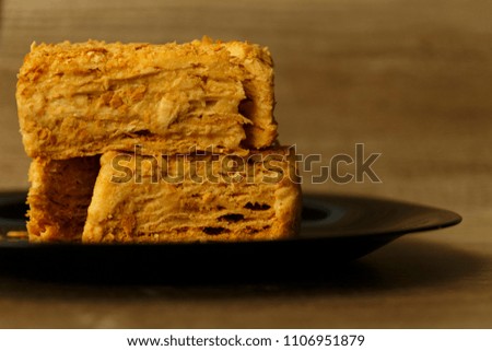 Slice of orange cake on black plate on the wooden table, food background