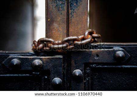 old metal gates are covered with a rusty metal chain. In an urban environment.
