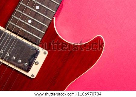 Close-up of red electric guitar on pink background. Musical concept of guitar music