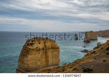 The famous sandstone steep rock in the 12 Apostles national park near Melbourne, Australia. Amazing view of the blue ocean gulf with sandy beaches under dark cloudy sky.