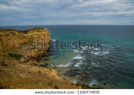 The famous sandstone steep rock in the 12 Apostles national park near Melbourne, Australia. Amazing view of the blue ocean gulf with sandy beaches under dark cloudy sky.