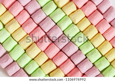 Background from bright colorful marshmallow. Diagonal rows of marshmallows. Geometric pattern from soft sweets.