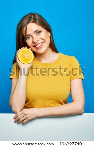 Woman holding orange fruit. Smiling girl portrait on blue.