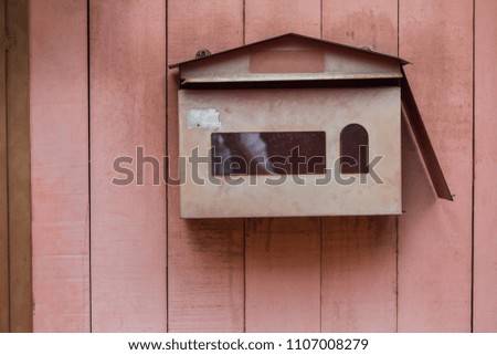 Close up and beautiful postbox or mailbox that is attached with pink wooden wall or fence outside the home for exterior design and decorative workings