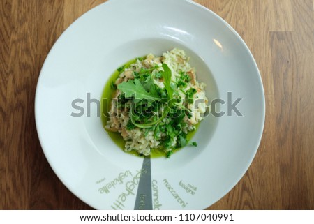 Green Risotto on round plate dish with Eruca sativa Rucula