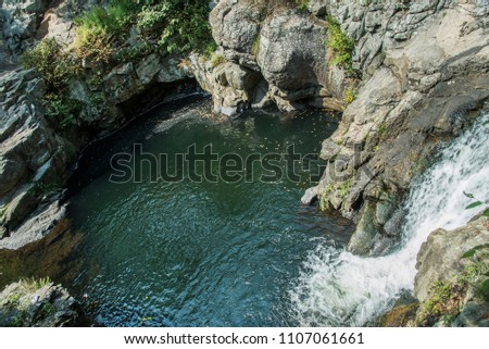 Waterfall pouring into a swimming hole. Royalty-Free Stock Photo #1107061661