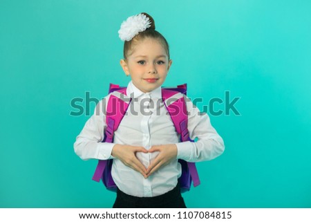 beautiful little happy girl in white shirt with bow on head and with briefcase on blue background