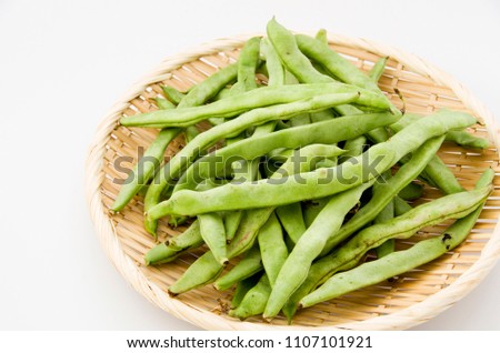 Flat green beans on bamboo sieve on white background.
