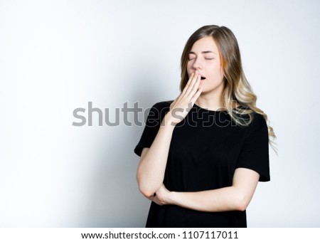 beautiful blond girl yawns, not enough sleep, isolated studio photo on background