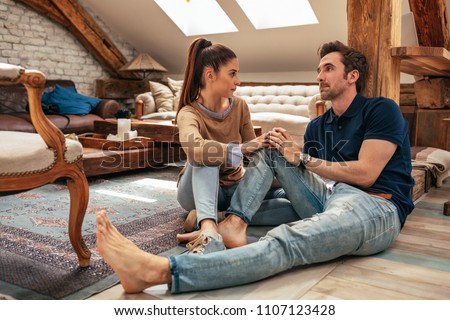 Horizontal shot of an attractive young couple talking in the living room Royalty-Free Stock Photo #1107123428