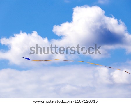 Flying a kite with a long tail during a hot summer day in Sweden. Blue sky and white clouds makes it a perfect day. 