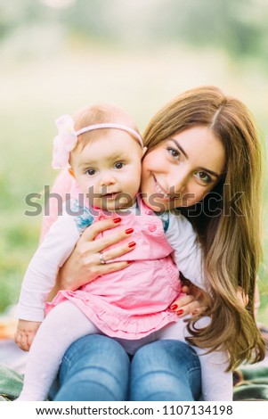 Happy cheerful family. Mother and baby kissing, laughing and hugging in nature outdoors