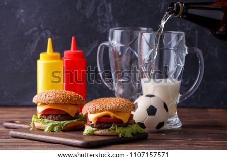 Image of two hamburgers, glasses, soccer ball, ketchup