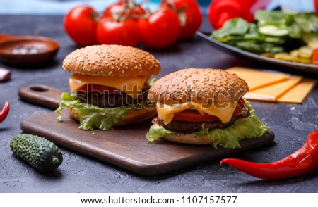 Image of two hamburgers on wooden board, cheese