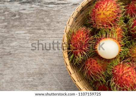 Fresh Rambutan in bamboo basket on wooden table background