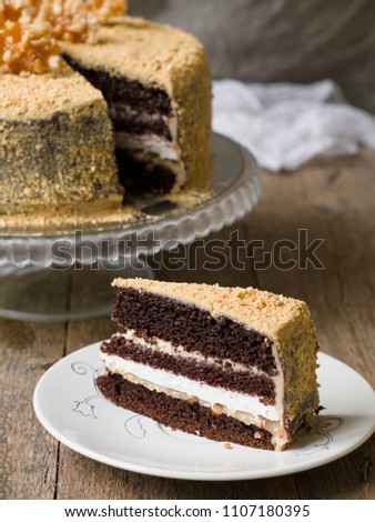 Chocolate cake with salted caramel, peanuts, decorated with chocolate, nuts and pieces of chocolate on a wooden background. Close up, copy space
