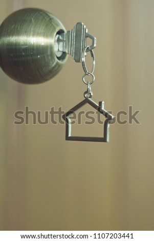 Home key with metal house keychain in keyhole, property concept