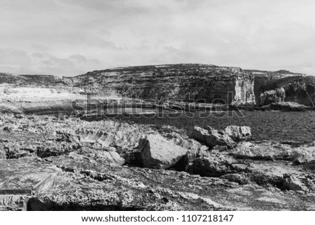 Gozo is a small island of the Maltese archipelago in the Mediterranean Sea.  Rugged coastline delineated by sheer limestone cliffs, and dotted with deep caves. Black and white picture