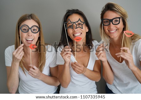 Girls having fun playing with photobooth props Royalty-Free Stock Photo #1107335945