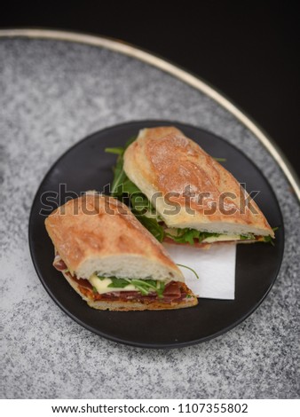 Freshly made panini with prosciutto, cheese, greens and pesto