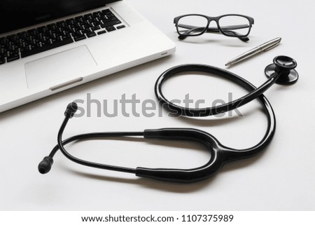 items doctor on desk , stethoscope , glasses , pen , laptop on white background