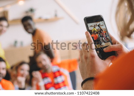cropped shot of man taking picture of friends on smartphone at home