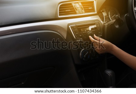Button on dashboard in car panel,Hand touching the screen and turning on car radio system