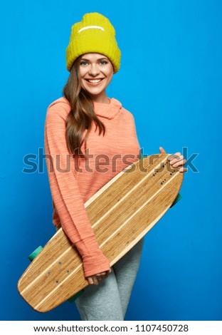 Modern young woman holding skateboard. Sporty girl on blue wal back.