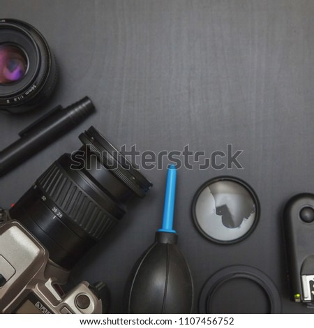 Top view of work space photographer with dslr camera system, camera cleaning kit, lens and camera accessory on black table background. Hobby journalism photography technology art concept
