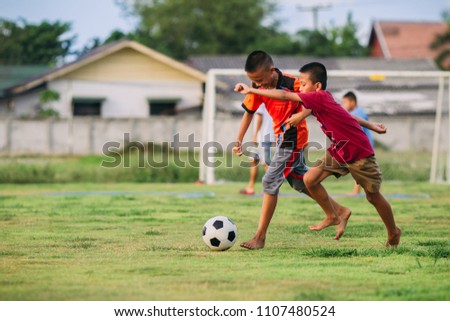 An action sport picture of a group of kid playing soccer football for exercise in community rural area under the sunset. Picture with copy space.