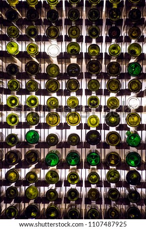 Wall of empty wine bottles. Empty wine bottles stacked-up on one another in pattern lit by the light coming from behind Royalty-Free Stock Photo #1107487925