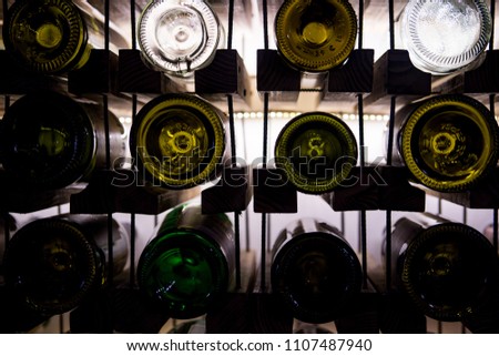 Wall of empty wine bottles. Empty wine bottles stacked-up on one another in pattern lit by the light coming from behind Royalty-Free Stock Photo #1107487940