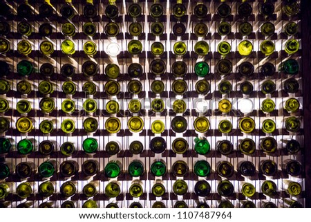 Wall of empty wine bottles. Empty wine bottles stacked-up on one another in pattern lit by the light coming from behind Royalty-Free Stock Photo #1107487964