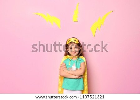 Cute girl in superhero costume on color background