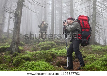 Traveling and photography. man with camera on tripod taking picture mountains forest.