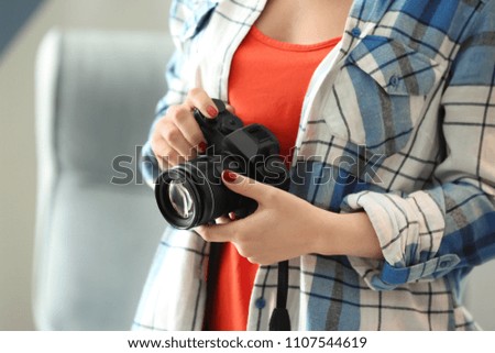 Young photographer with camera, indoors