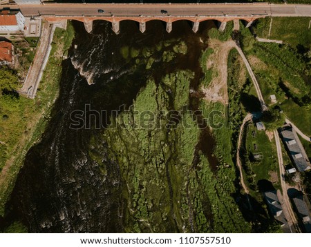 Aerial shot of Venta rapid waterfall in Europe, Kuldiga, Latvia with long brick bridge.