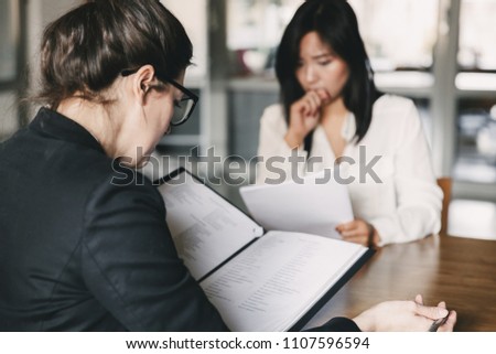 Photo from back of businesswoman interviewing and talking with nervous female applicant during job interview - business, career and placement concept Royalty-Free Stock Photo #1107596594