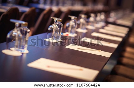 Image close up of White paper with pencil and glass with bottled water setup on the table for the speech of the lecture ,Prepare conference in the hotel. Royalty-Free Stock Photo #1107604424