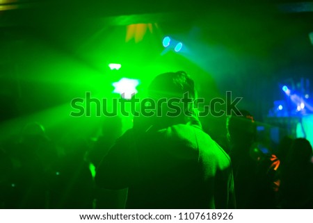 Party goers inside club venue with laser lighting